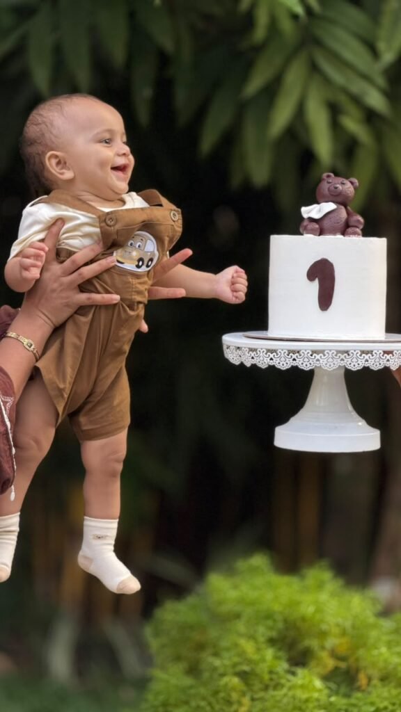 Smiling child beside a first birthday cake